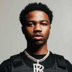 black man named roddyricch looks seriously into the camera, wears black clothes and gold jewelry