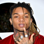 black man named swaelee makes hand signs with his hand and looks into the camera